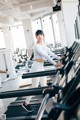 A woman is running on a treadmill in a gym.