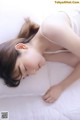 A woman laying on a bed with her eyes closed.