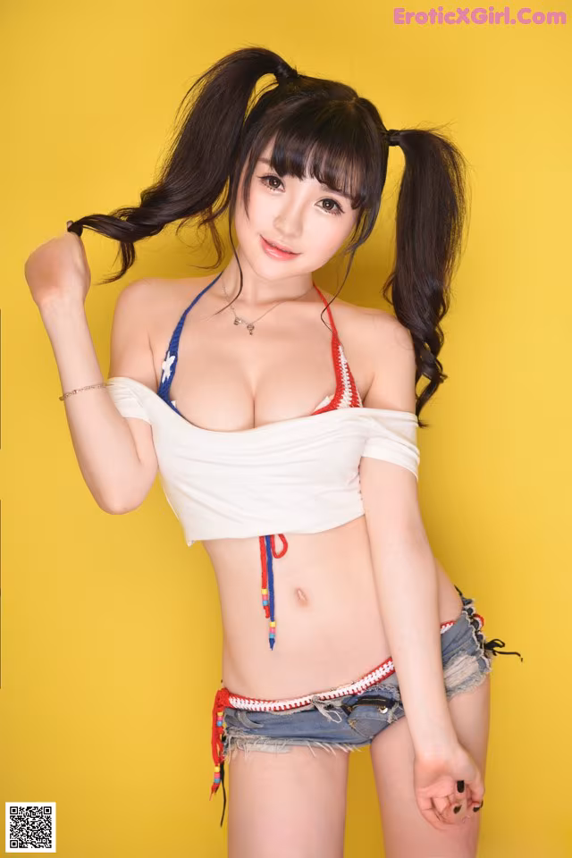 A woman in a white top and denim shorts posing for a picture.
