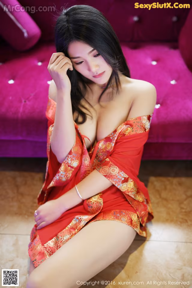 A woman in a red dress sitting on a purple couch.
