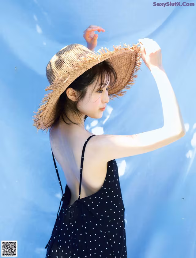 A woman in a black dress and a straw hat.