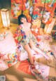 A woman in a colorful kimono sitting on a bed.