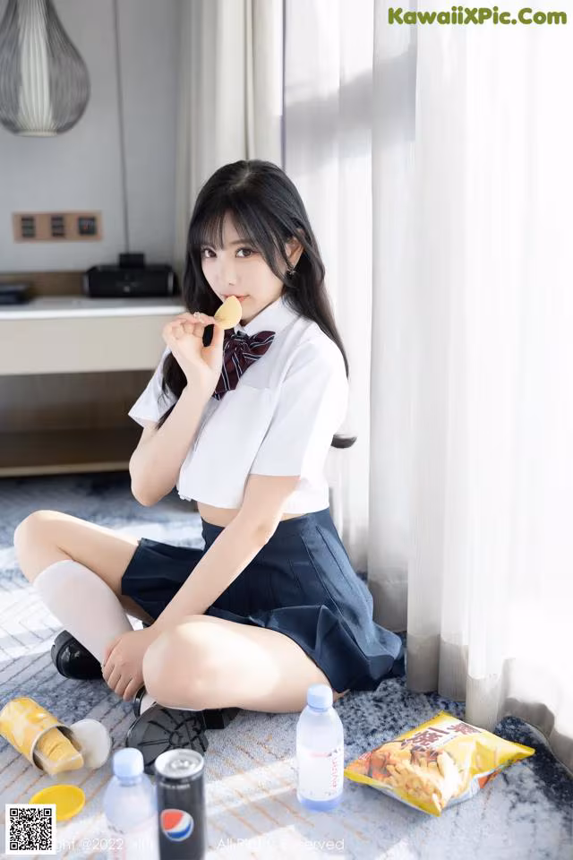 A woman sitting on the floor eating a piece of food.