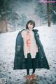 A woman standing in the snow wearing a black coat.