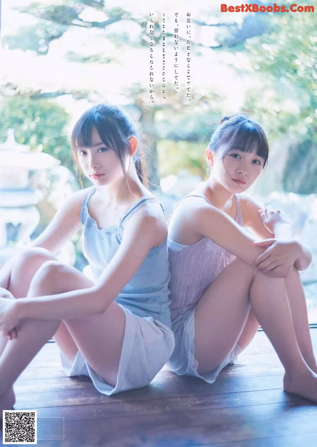 Two young women sitting on a wooden floor next to each other.
