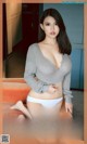 A woman in a gray sweater and white panties posing for a magazine cover.