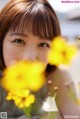 A young woman with a bunch of yellow flowers in front of her.