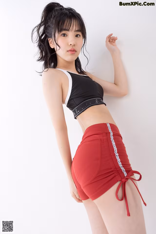 a woman in a black top and red shorts posing for a picture