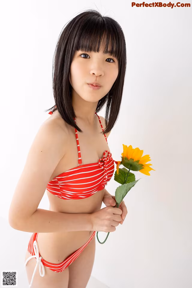 A woman in a red and white striped bikini holding a sunflower.