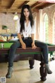 A woman sitting on top of a pool table.