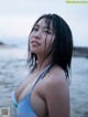 A woman in a blue bikini standing in the water.