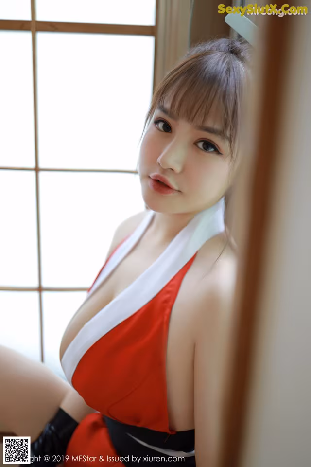 A woman in a red and white dress sitting on a window sill.