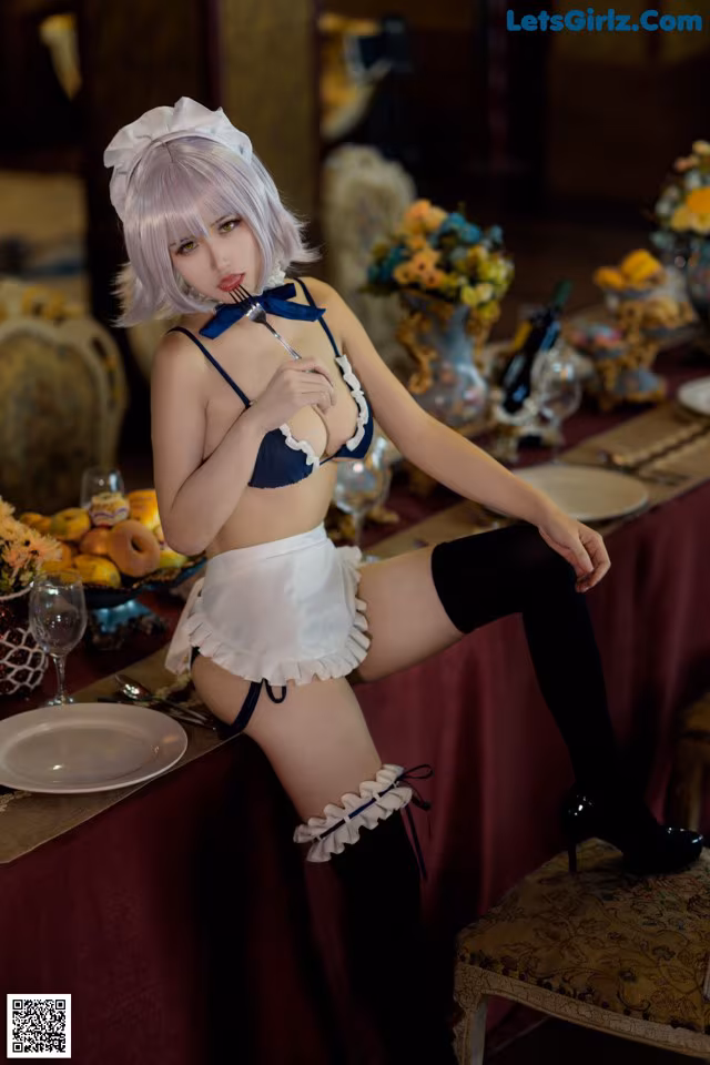A woman in a maid outfit sitting at a table.