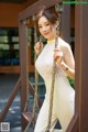 A woman in a white dress is posing on a swing.