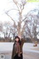 A woman standing in front of a large tree.