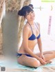 a woman in a blue bikini sitting on a towel on the beach