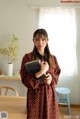 A woman standing in front of a table holding a book.