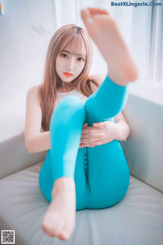 A woman sitting on top of a white couch with her legs crossed.