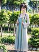 A woman in a blue and white dress standing in a park.