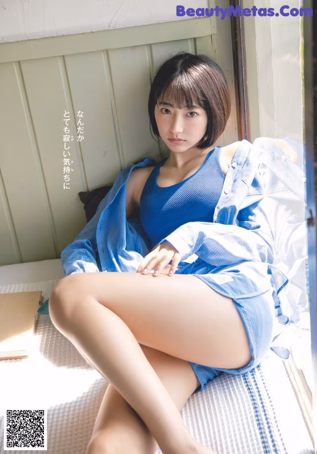 A woman sitting on a bed with her legs crossed.
