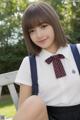 A young woman in a school uniform sitting on a bench.