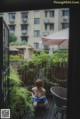 A woman sitting on a wooden deck next to a fence.