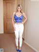 A woman in a blue bra top and white jeans posing for the camera.