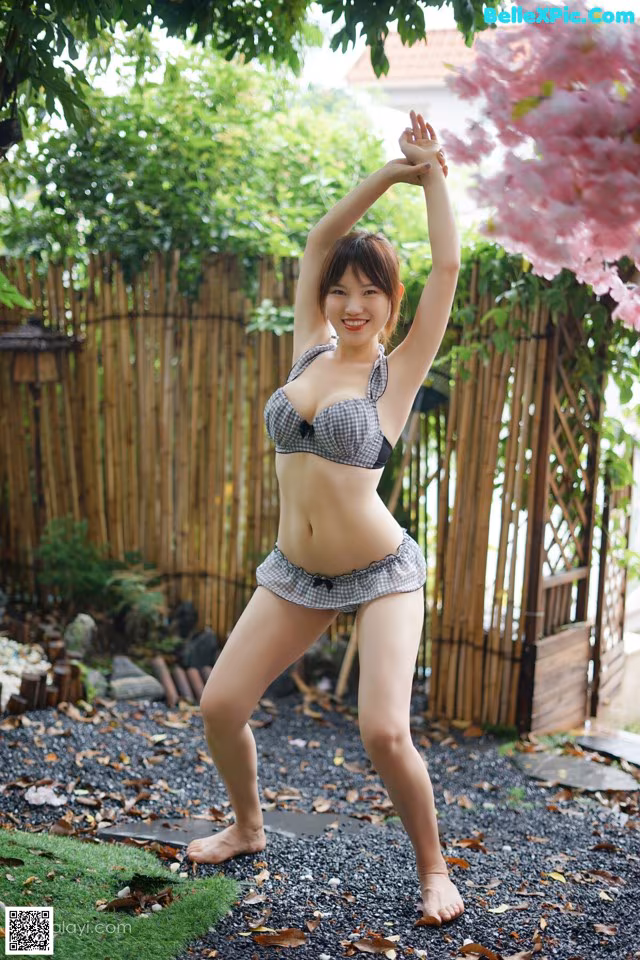 A woman in a bikini posing in a garden.