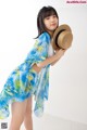 A woman in a blue and yellow dress holding a straw hat.