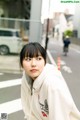 A woman in a white hoodie standing on a city street.