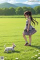 A girl walking a dog in a field of flowers.