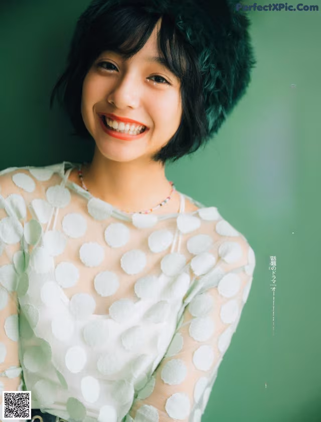 A woman in a white polka dot dress smiles at the camera.